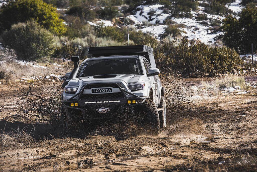 Toyota Tacoma with 35" tires offroad running through the mud