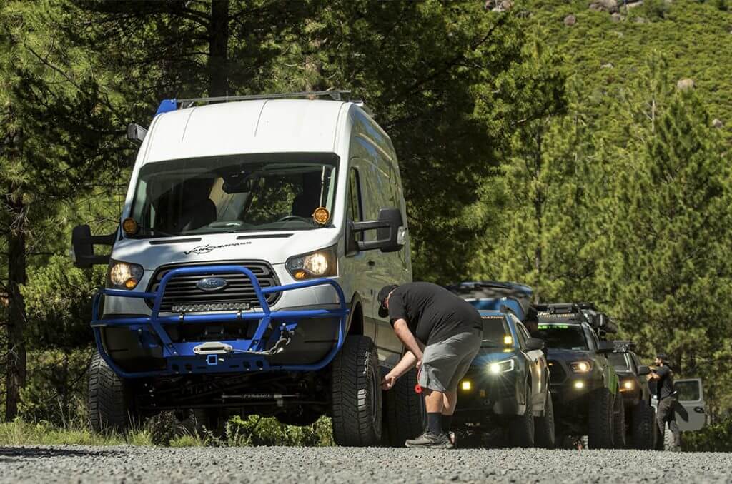Ford transit van on milestar X/T tires followed by a blue subaru wilderness and a toyota tacoma
