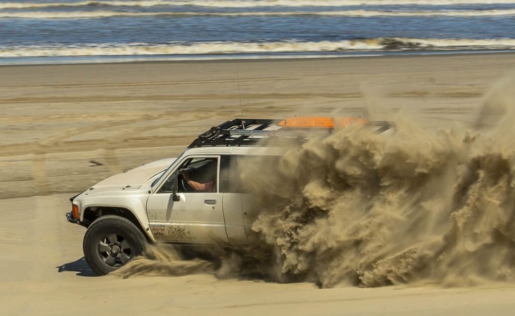 white toyota pick up tears up the sand on an Oregon beach