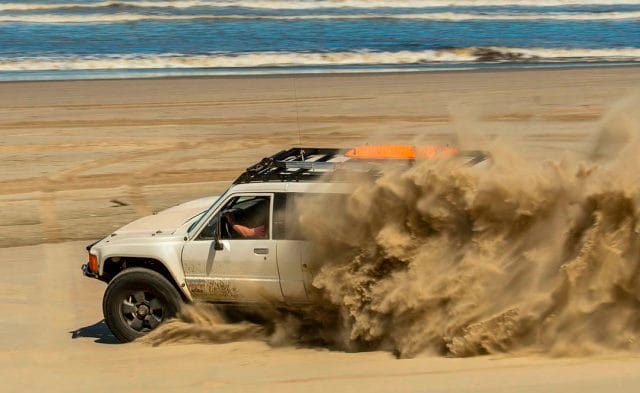 white toyota pick up tears up the sand on an Oregon beach